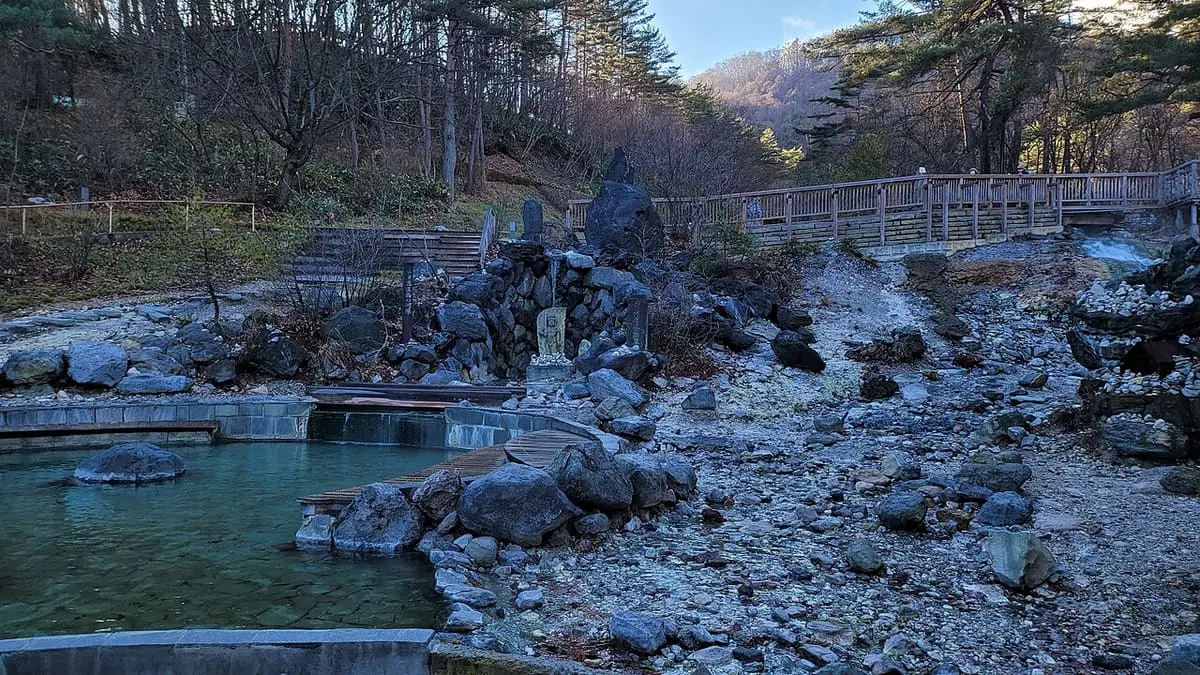 Turquoise hot water pool among rocks in Sainokawara Park, Kusatsu