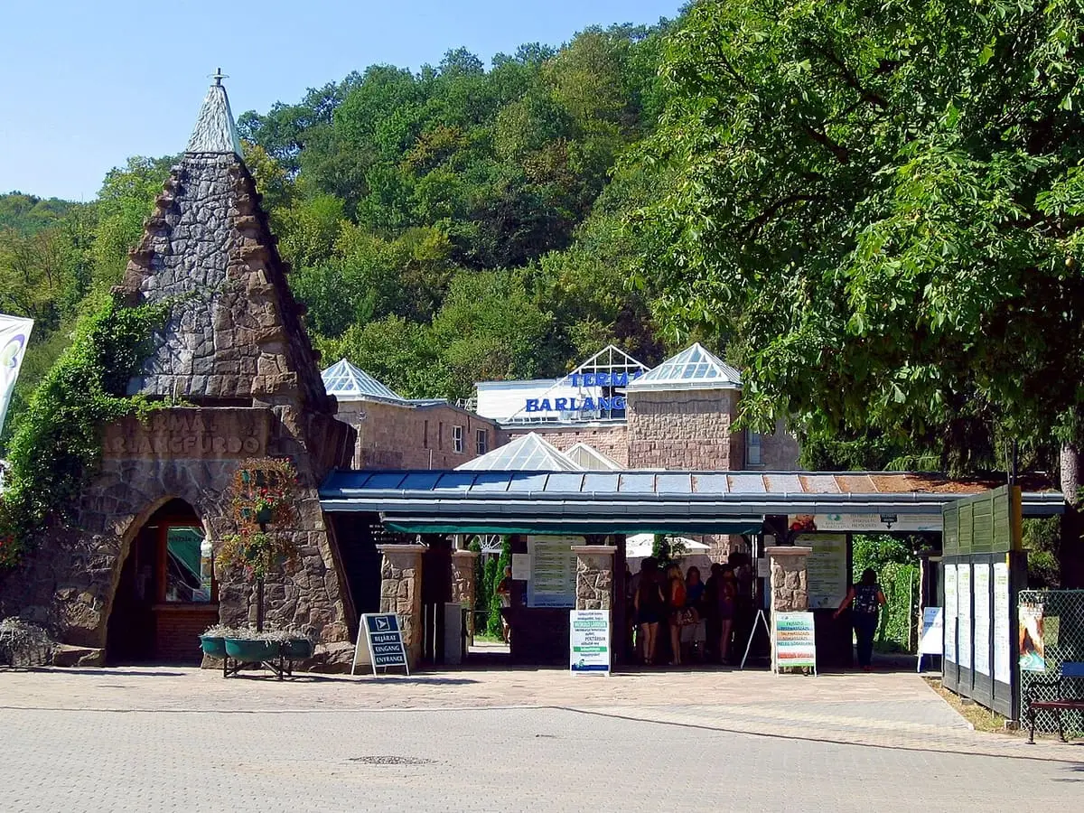 Entrance to the Miskolctapolca cave bath with a stone pyramid tower and green hills