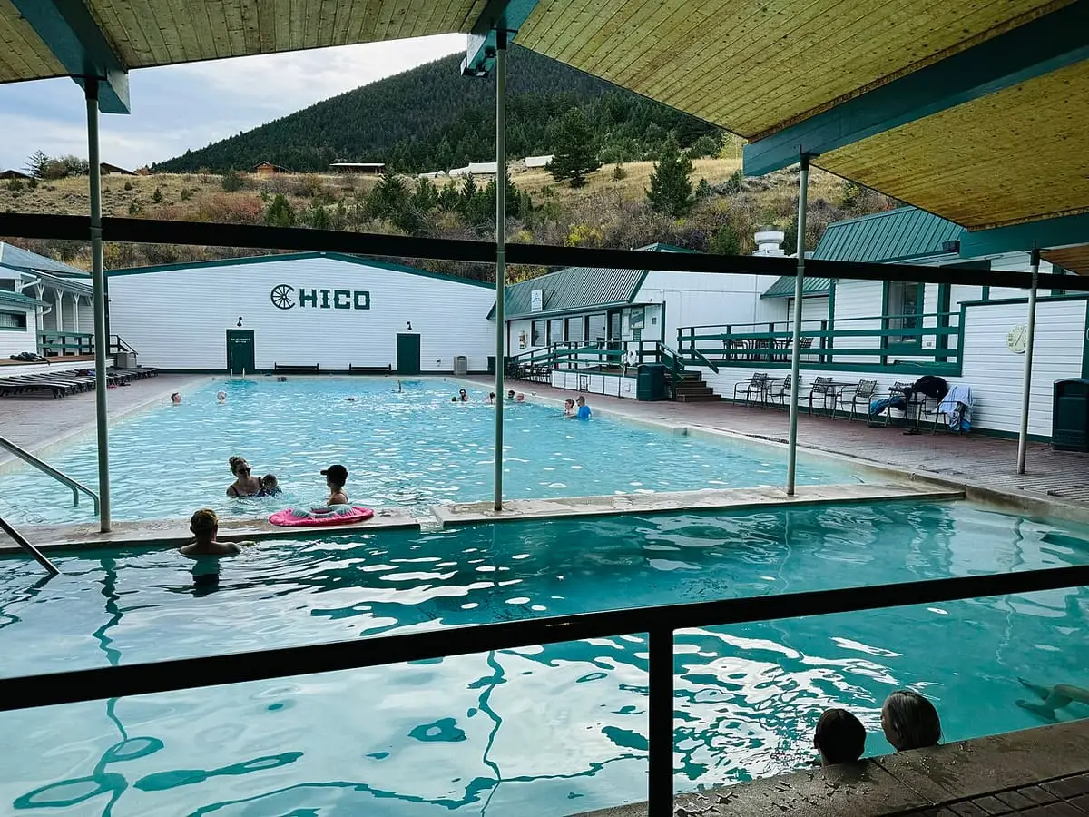 Chico Hot Springs pools seen from under a covered deck with forested hills beyond