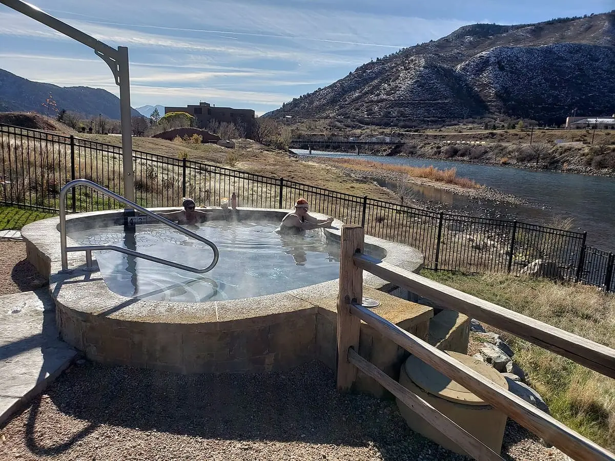 Small round soaking pool beside a railing overlooking the Colorado River at Iron Mountain Hot Springs