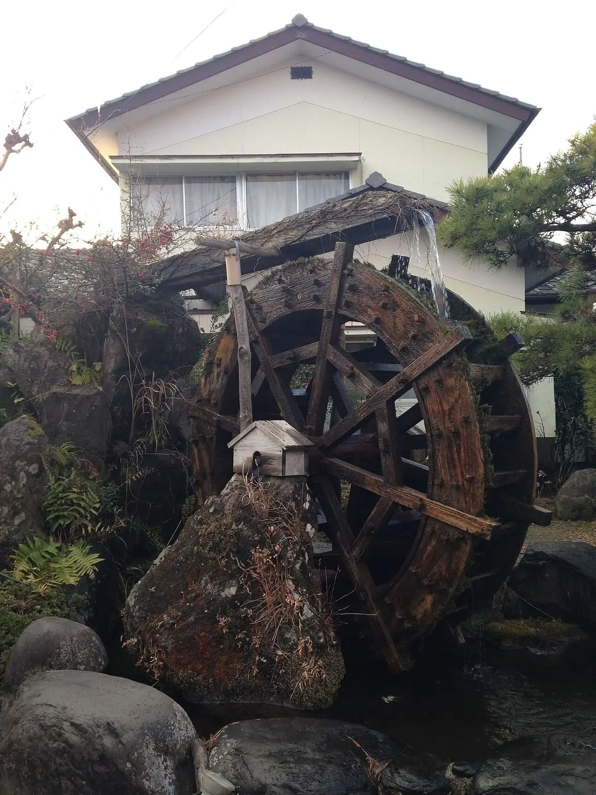 Wooden water wheel beside a rock garden at an inn in Yufuin Onsen