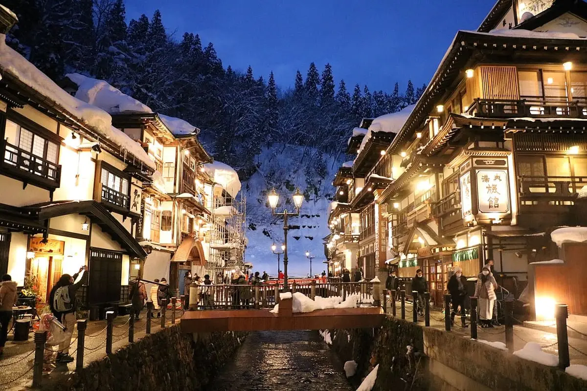 Multi storey wooden inns of Ginzan Onsen glowing with lamps on a snowy evening