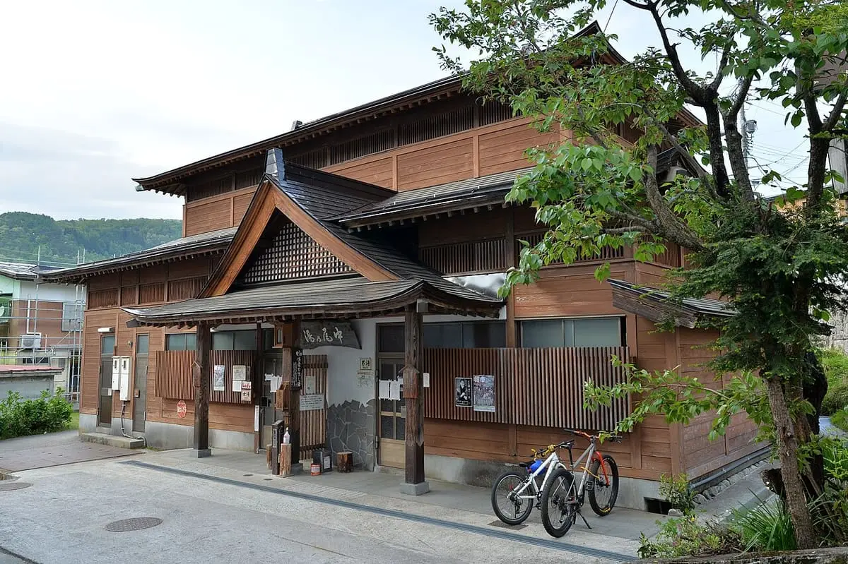 Wooden Nakao no Yu bathhouse with a curved gable roof in Nozawa Onsen