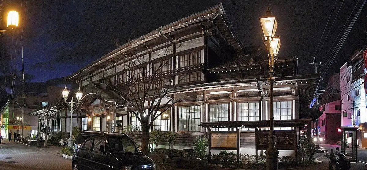 Takegawara Onsen bathhouse lit by street lamps at night in Beppu