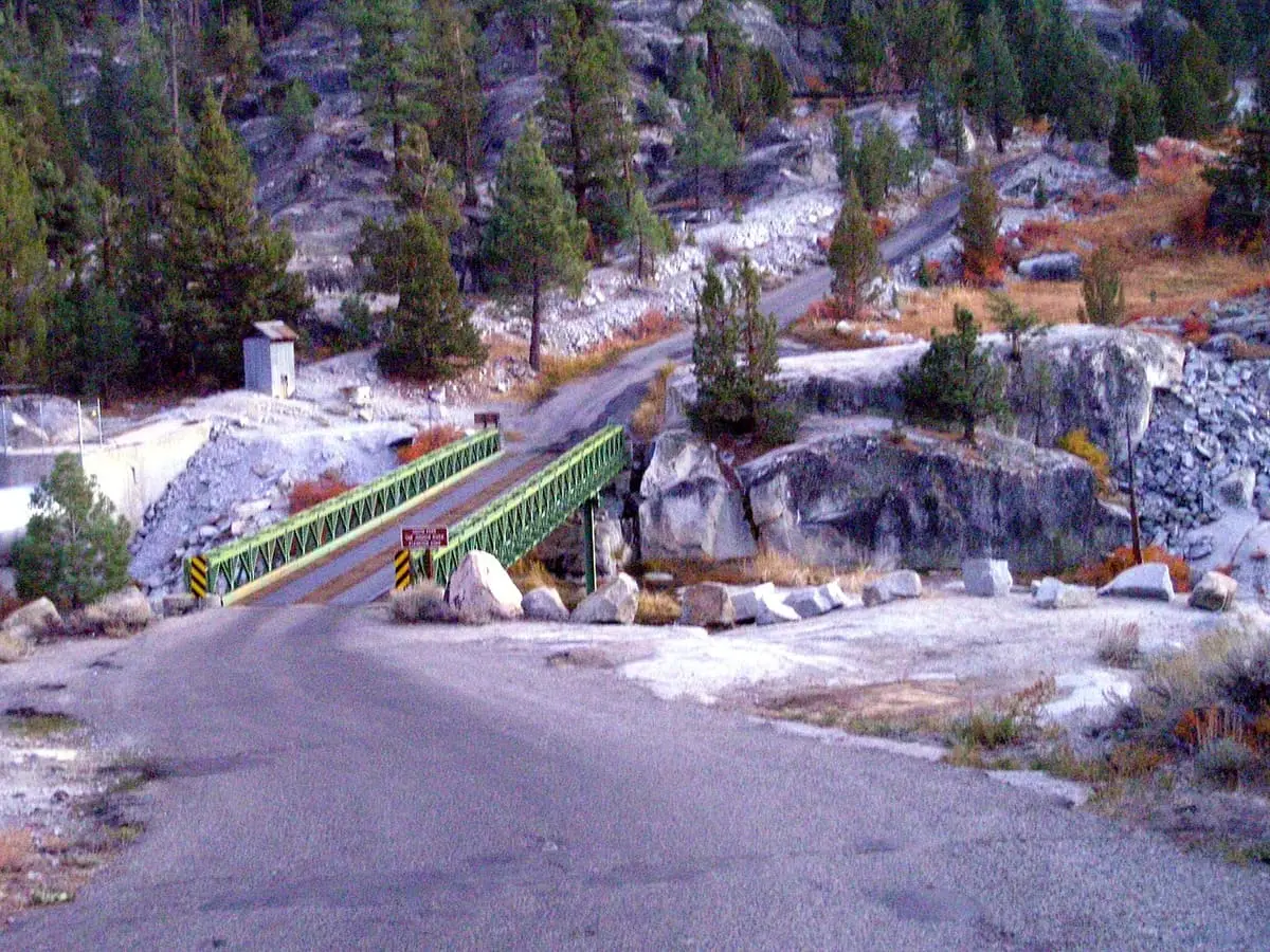 Paved road and green bridge over the river near Mono Hot Springs among granite and pines