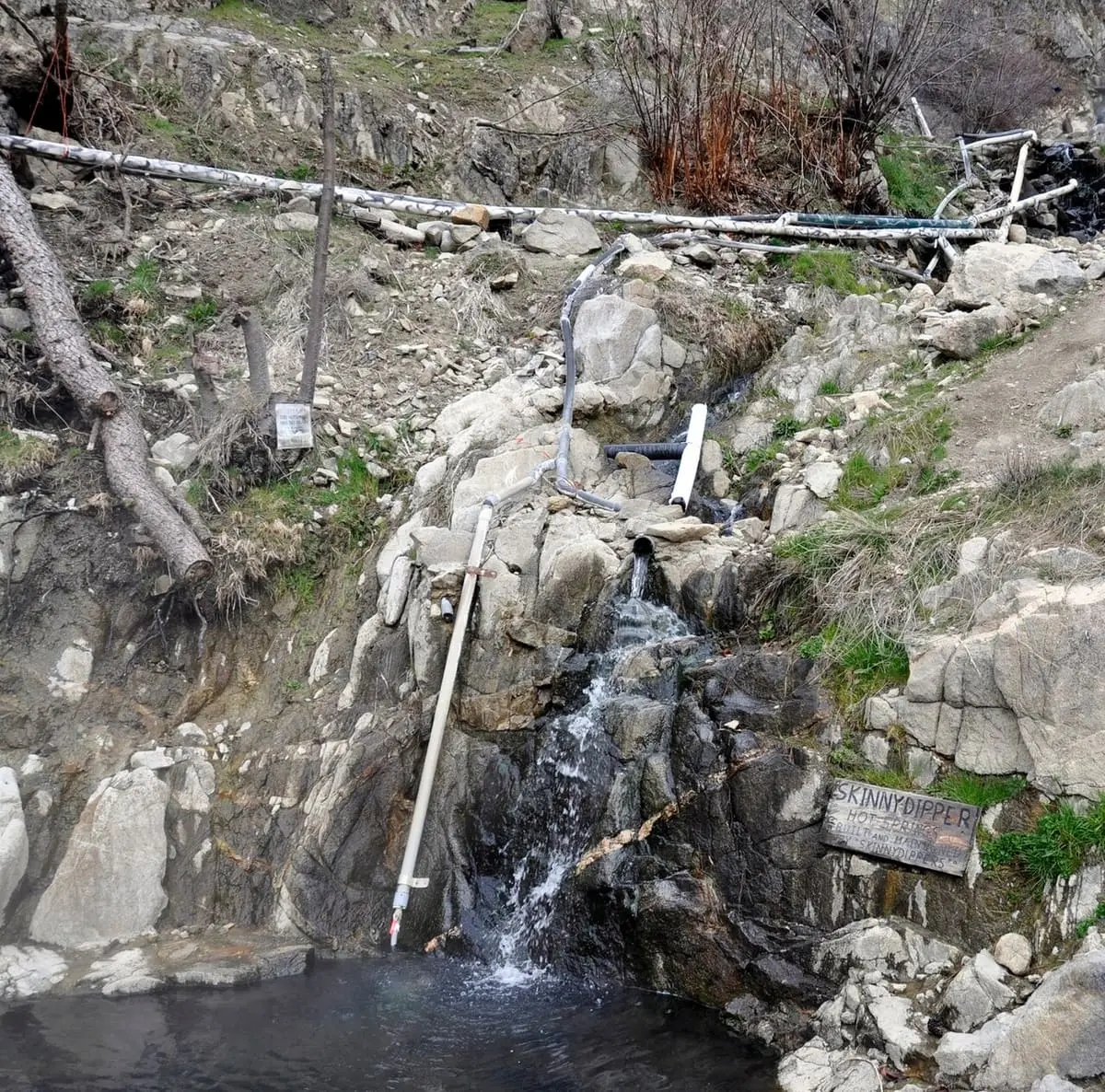 Small waterfall spilling into a pool below piping at Skinny Dipper Hot Springs