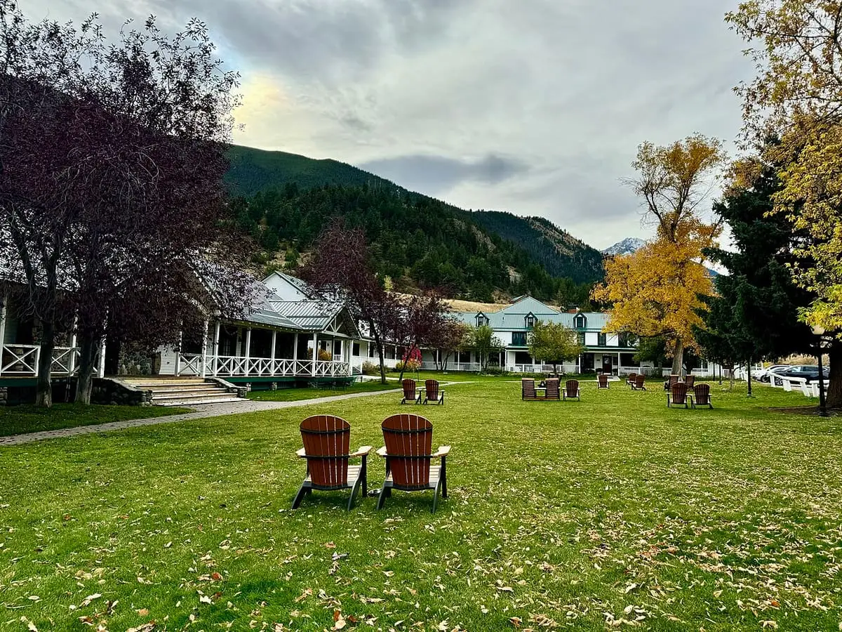Lawn with red Adirondack chairs and autumn trees in front of the Chico Hot Springs buildings