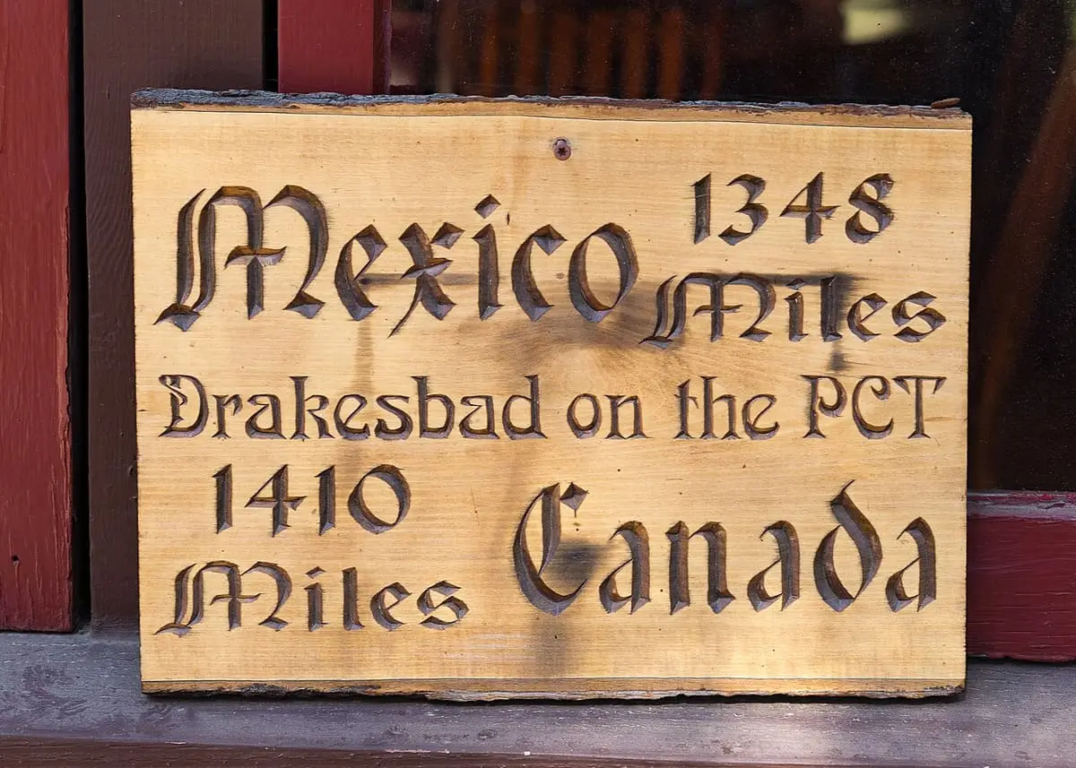 Carved wooden sign at Drakesbad on the PCT reading Mexico 1348 miles and Canada 1410 miles
