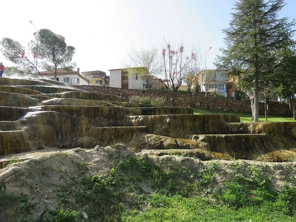Stepped mineral terraces at Kırmızı Su in Karahayıt below trees and village houses