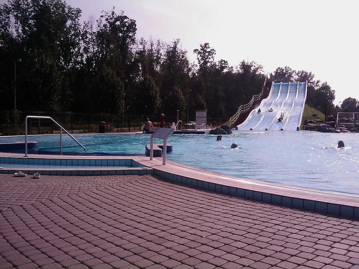 Outdoor pool and white water slides beside trees at the Sárvár spa