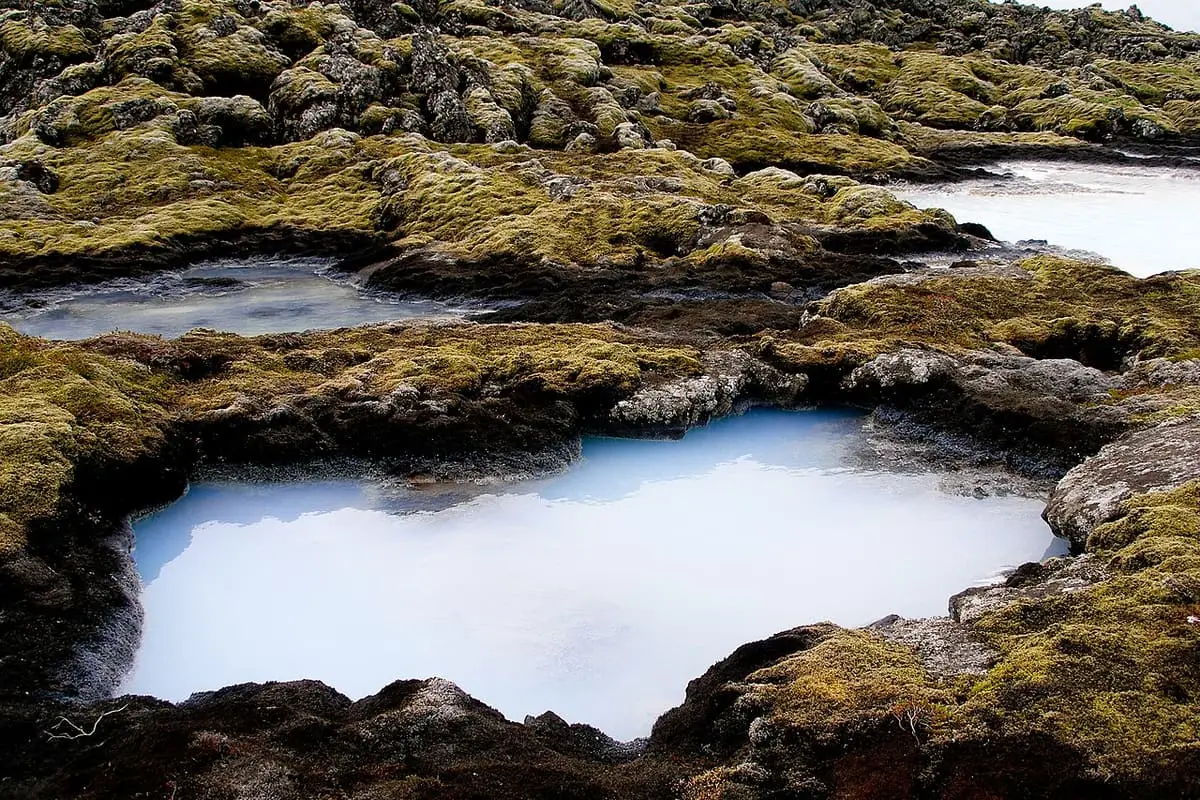 Milky blue geothermal pool in mossy lava rock beside the Blue Lagoon