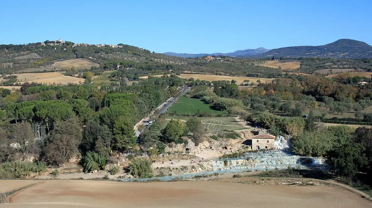 Panorama over the green Maremma hills with the Saturnia cascades in the valley below