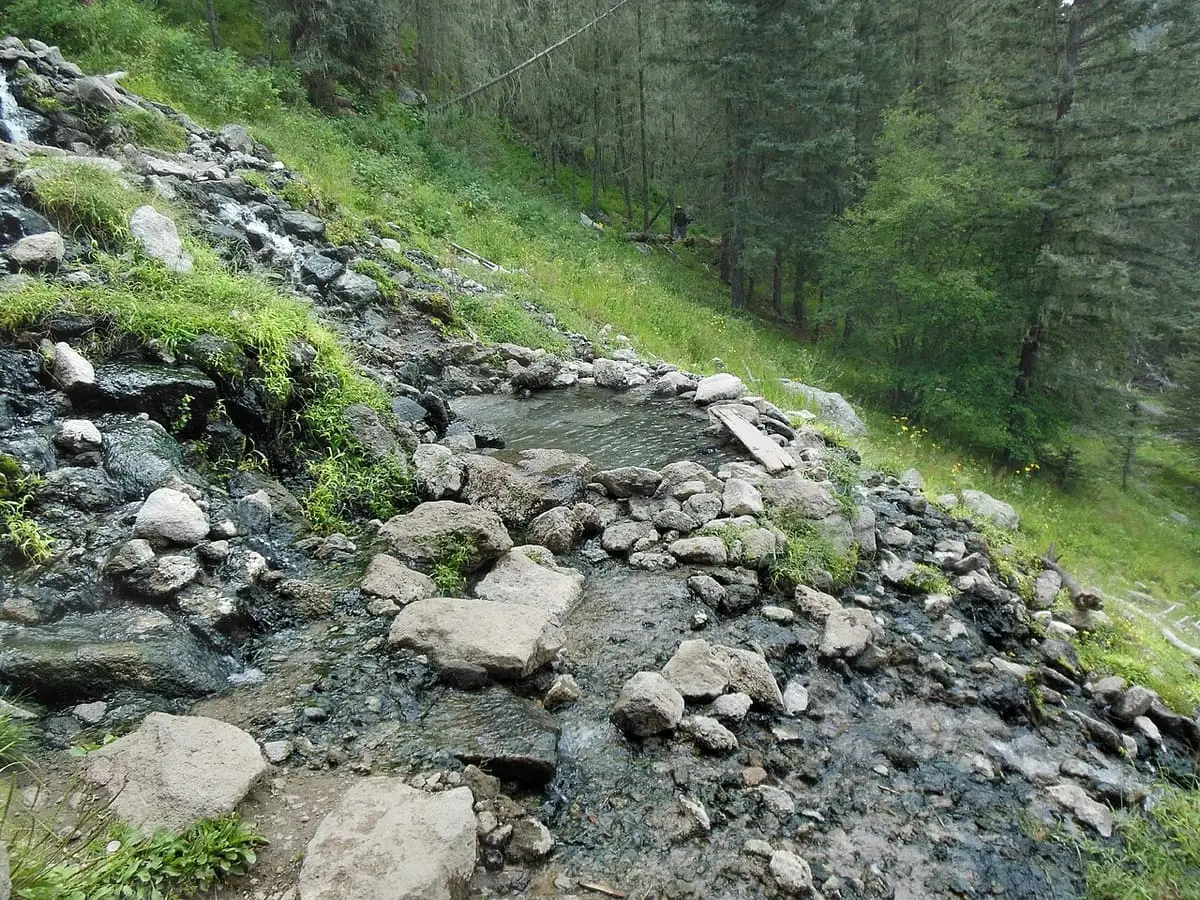 Rocky runoff channel and pools on the grassy hillside at San Antonio Hot Springs