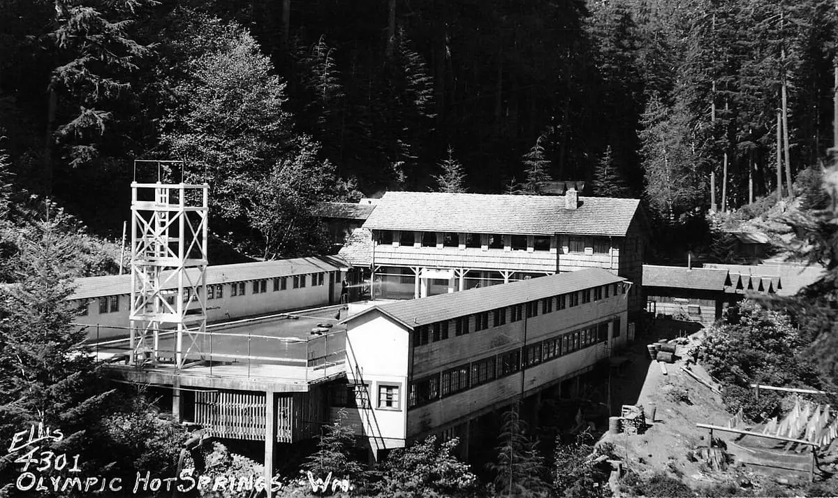 Historic postcard of the former Olympic Hot Springs resort buildings in a forested valley