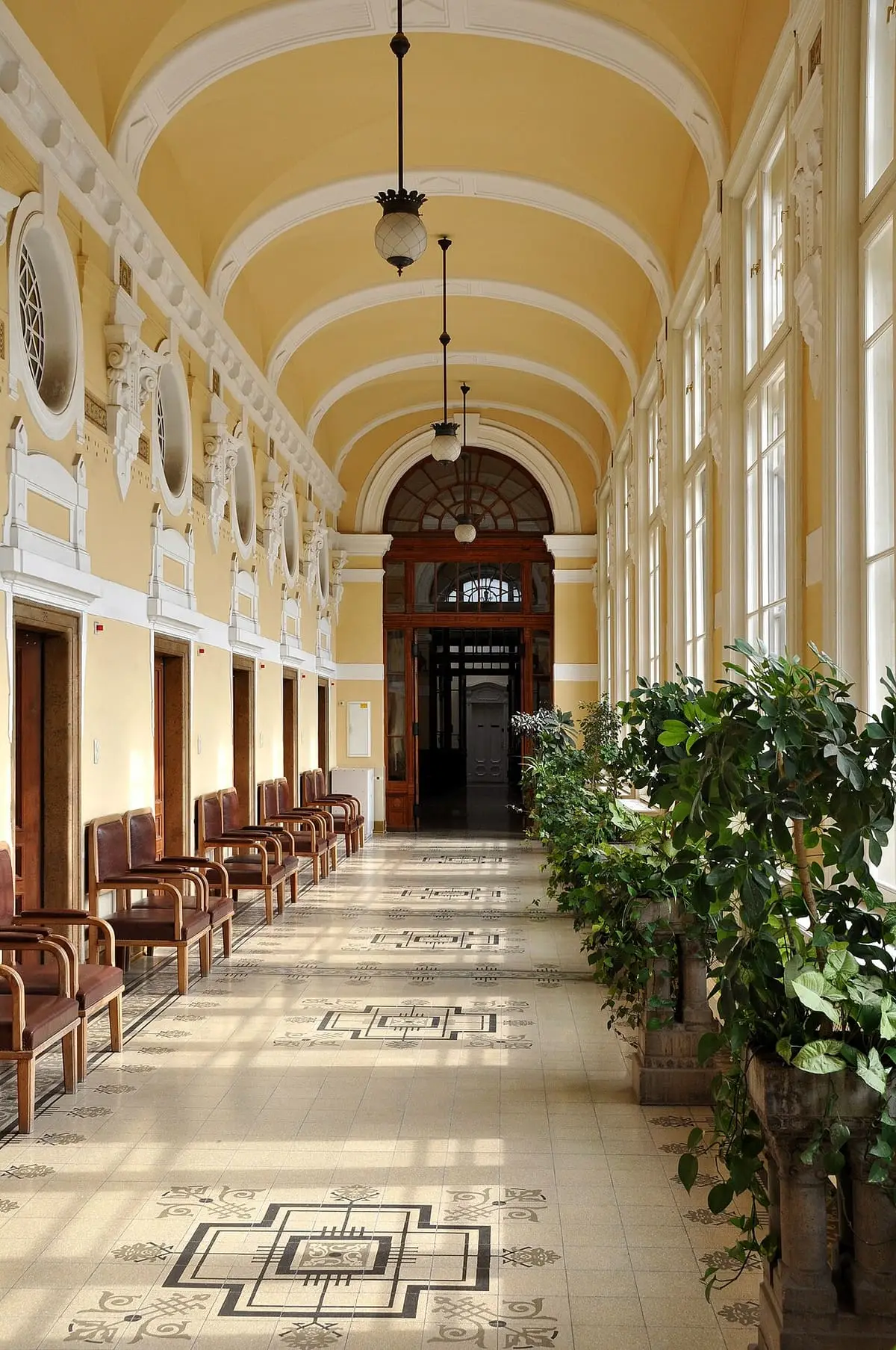 Vaulted yellow corridor with tiled floor and lanterns inside the Széchenyi bath building
