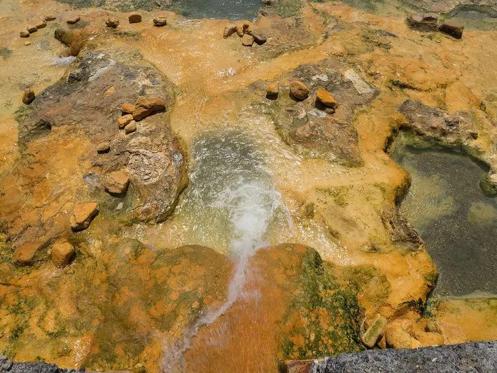 Hot spring water flowing over orange mineral crusted rock at Loutra Edipsou on Evia