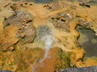Hot spring water flowing over orange mineral crusted rock at Loutra Edipsou on Evia
