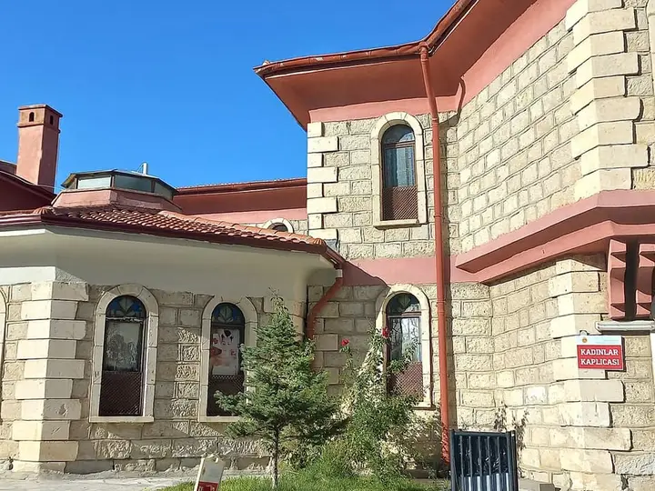 Stone and red trimmed Gazlıgöl thermal bath building with a women's bath entrance sign