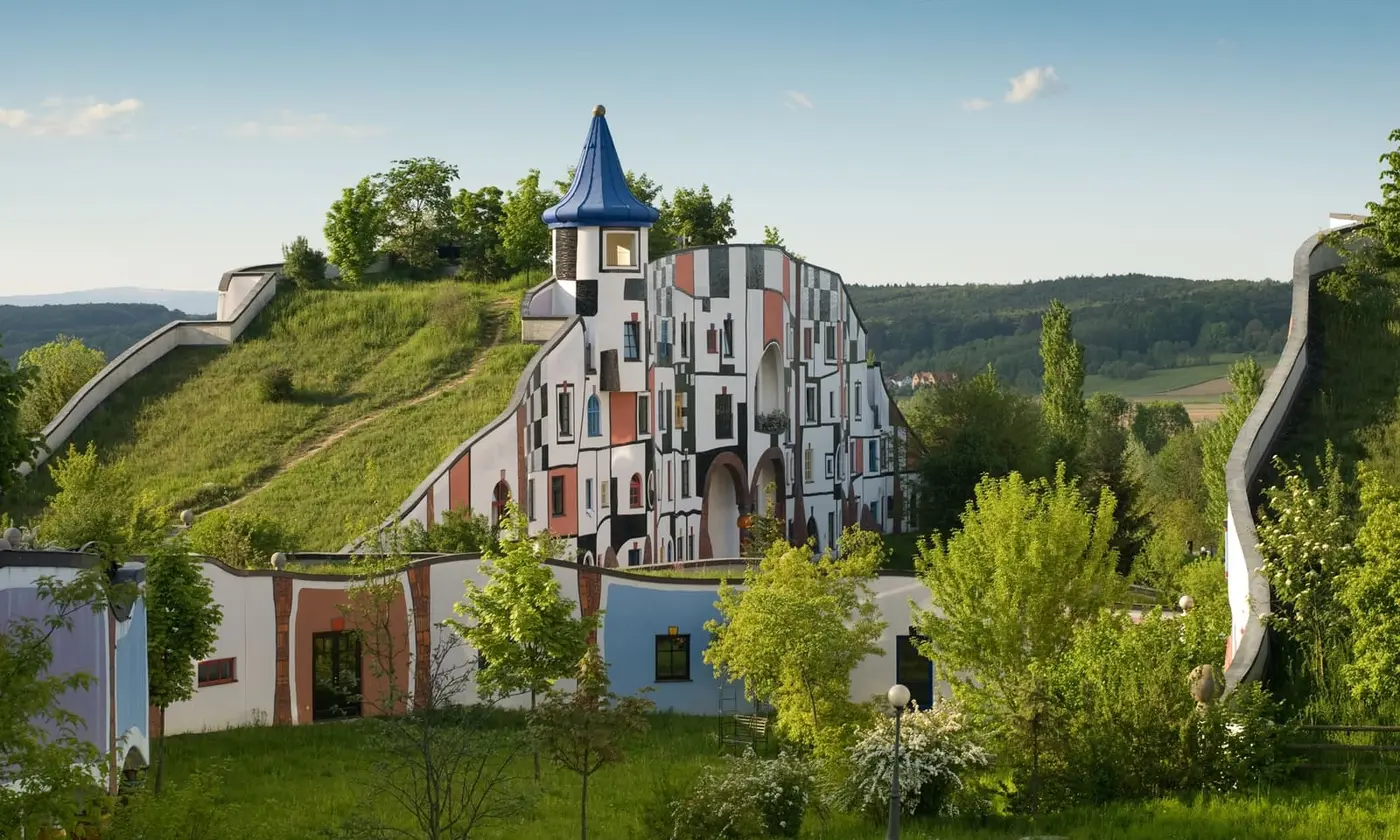 Colorful Hundertwasser Kunsthaus building with grass roof and golden spire at Rogner Bad Blumau