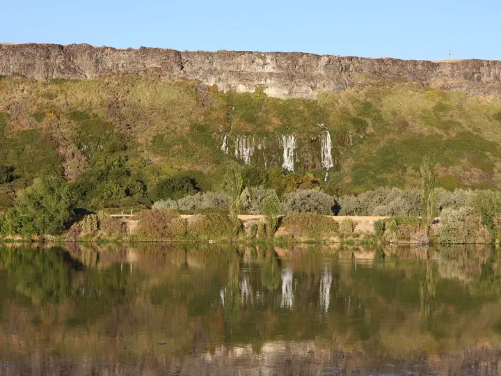 Spring water spilling from the Thousand Springs basalt cliffs and reflected in the Snake River near 1000 Springs Resort
