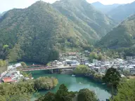Totsukawa Onsen town beside the green waters of Lake Futsuno, surrounded by forested mountains