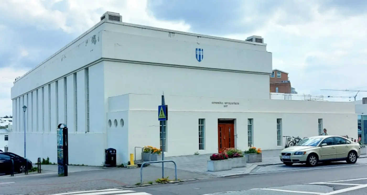 White 1937 Sundhöll Reykjavíkur building with tall columns and a red entrance door