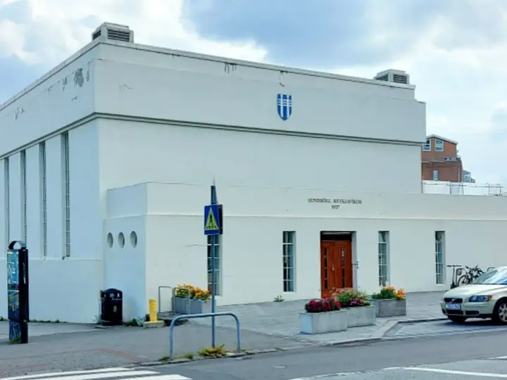 White 1937 Sundhöll Reykjavíkur building with tall columns and a red entrance door