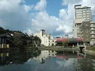 Hotels of Wakura Onsen reflected in still water under a cloudy blue sky