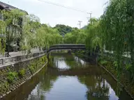 Willow lined Otani River canal and stone arched bridge in Kinosaki Onsen