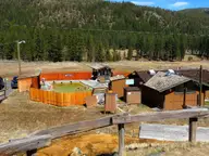 Fenced hot spring pool complex at Grover Hot Springs State Park below pine covered hills