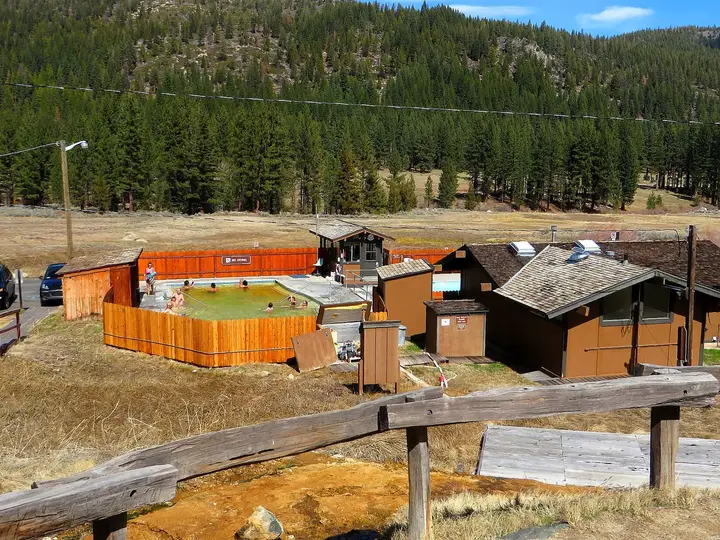 Fenced hot spring pool complex at Grover Hot Springs State Park below pine covered hills