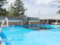 Cove Warm Springs Pool, a large clear blue outdoor pool beside low white buildings