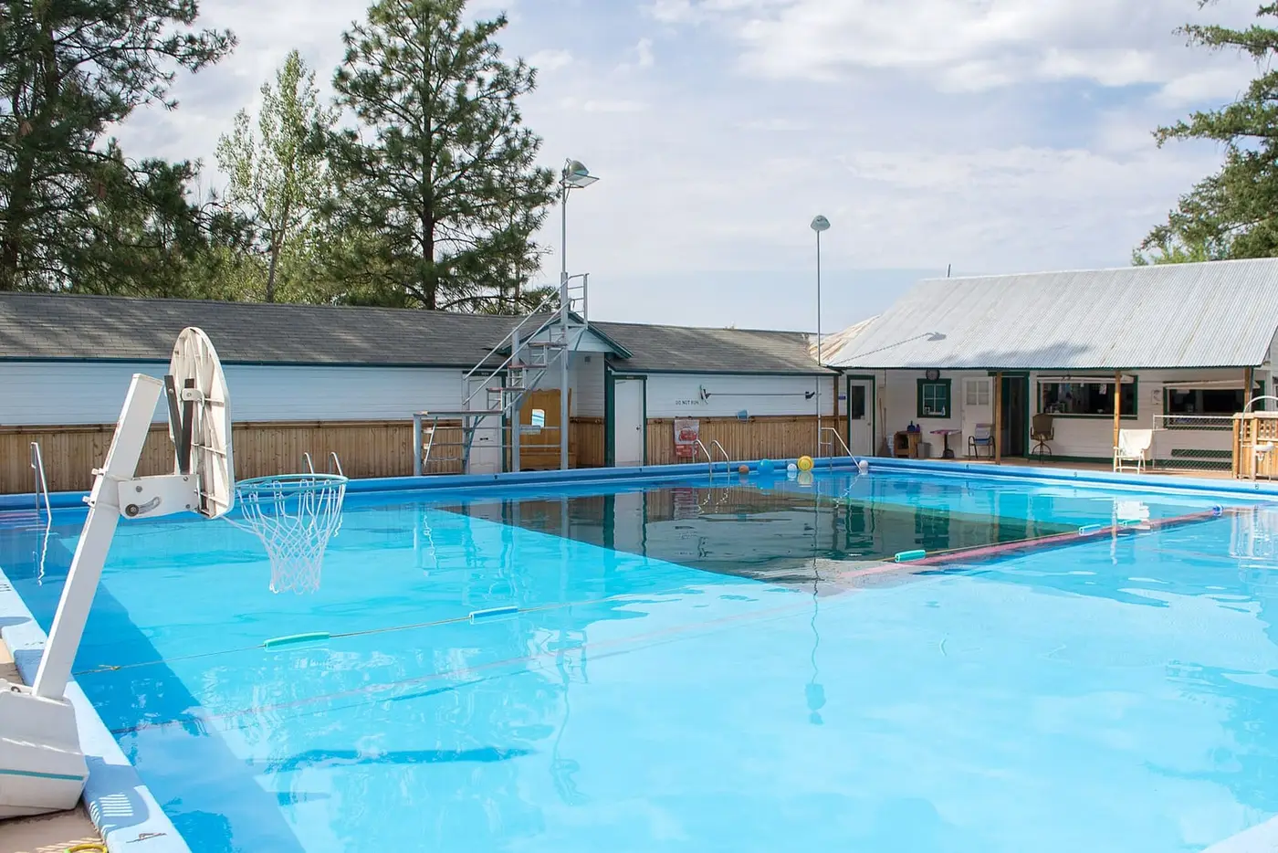 Cove Warm Springs Pool, a large clear blue outdoor pool beside low white buildings