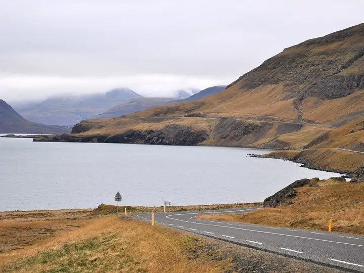 Road 47 curving along Hvammsvík bay in Hvalfjörður below brown mountain slopes