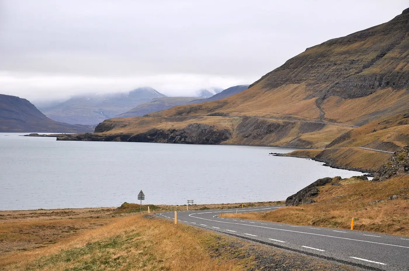 Road 47 curving along Hvammsvík bay in Hvalfjörður below brown mountain slopes