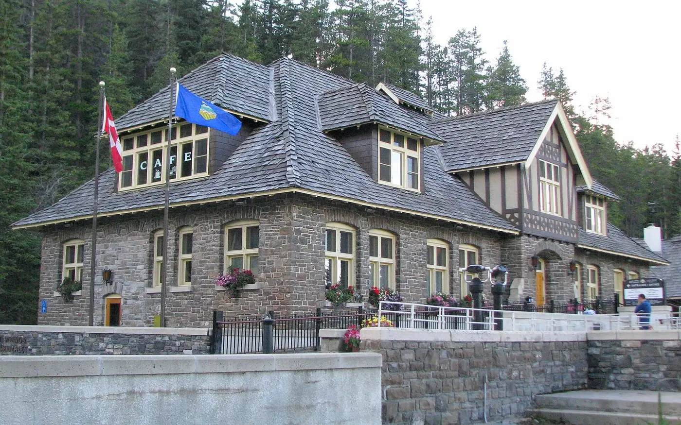 Stone Upper Hot Springs bathhouse in Banff with flags and pine forest behind