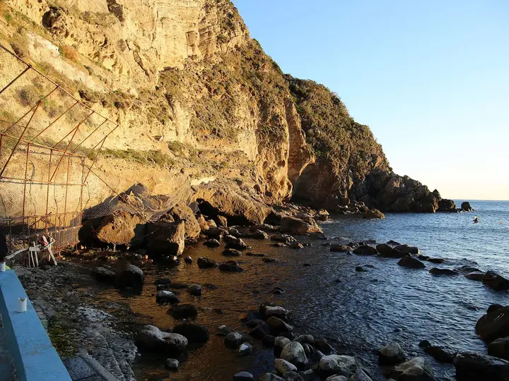 Boulders and sunlit cliffs at Baia di Sorgeto on Ischia, where hot springs flow into the sea