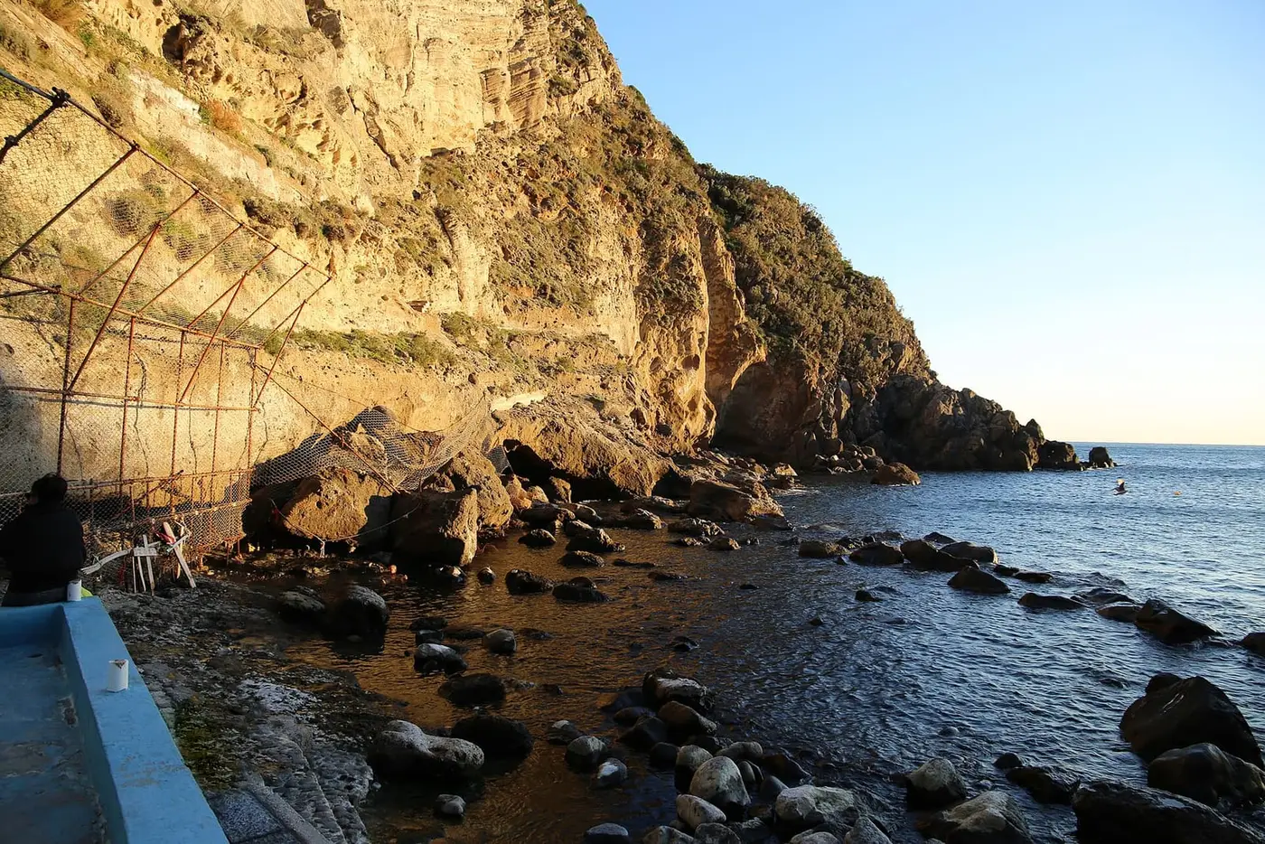 Boulders and sunlit cliffs at Baia di Sorgeto on Ischia, where hot springs flow into the sea