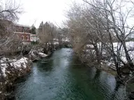 Portneuf River flowing past a brick building and bare winter trees in Lava Hot Springs
