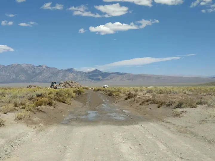 Dirt access road to Wild Willy's Hot Spring crossing sagebrush in Long Valley toward distant mountains