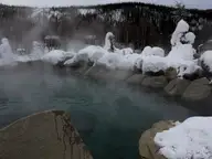 Steaming rock lined hot springs lake under heavy snow at Chena Hot Springs Resort