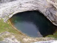 Dark green spring water at the bottom of Diana's Punch Bowl, a sheer walled travertine crater