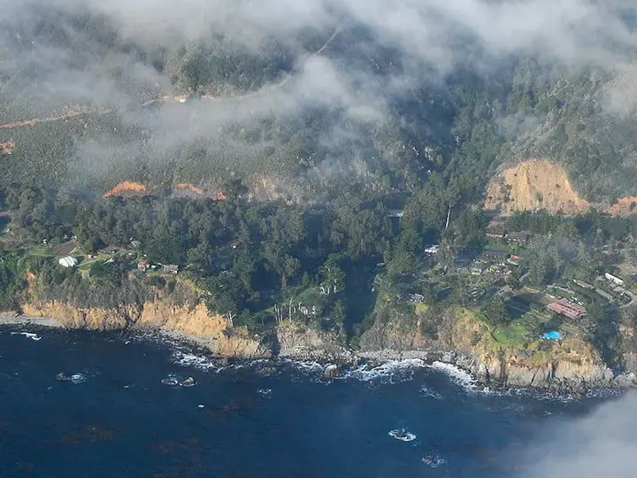 Aerial view of the Esalen Institute grounds on the Big Sur coastline under low evening clouds