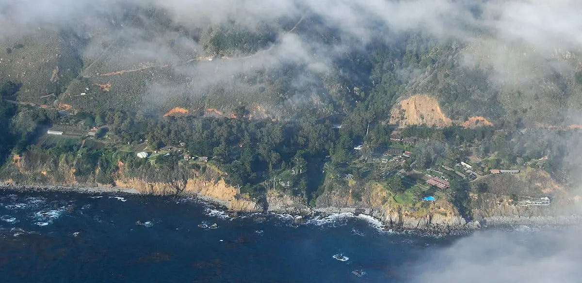 Aerial view of the Esalen Institute grounds on the Big Sur coastline under low evening clouds