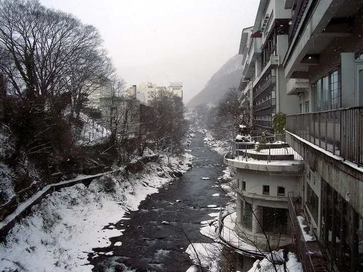 Snowy Tone River gorge lined with tall ryokan buildings at Minakami Onsen