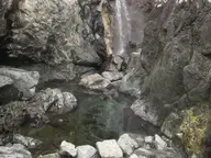 Steaming hot waterfall pouring between rocks into a clear pool at Hot Springs Cove