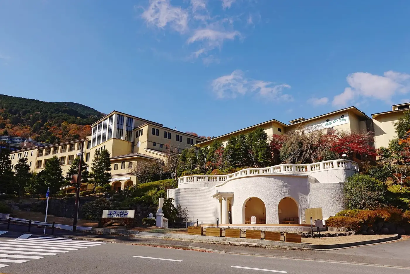 Hakone Kowakien Yunessun resort buildings with a white arched entrance among autumn hills