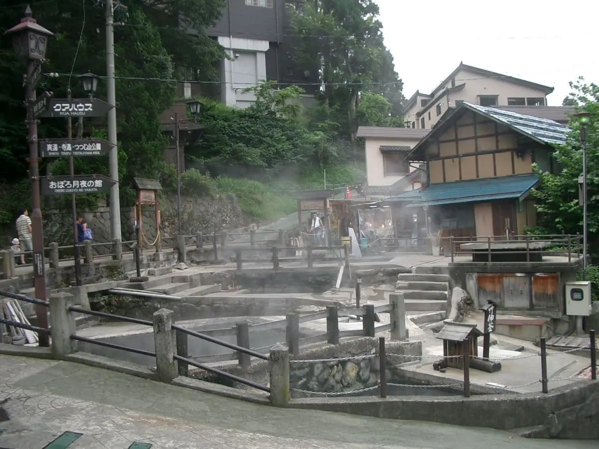 Steaming Okama hot spring pools surrounded by stone walls and railings in Nozawa Onsen