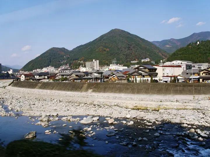 Gero Onsen hotels lining the rocky Hida River below green mountains on a clear day