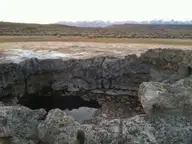 Shallow water inside the rough sinter collar of the Paradise Valley hot spring with snowy Santa Rosa Mountains beyond